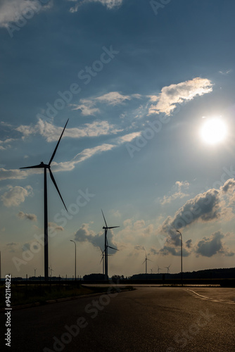 Obraz na płótnie Wind turbines and high voltage electric pylon against blue sky. Sun shining behind the turbines w salonie