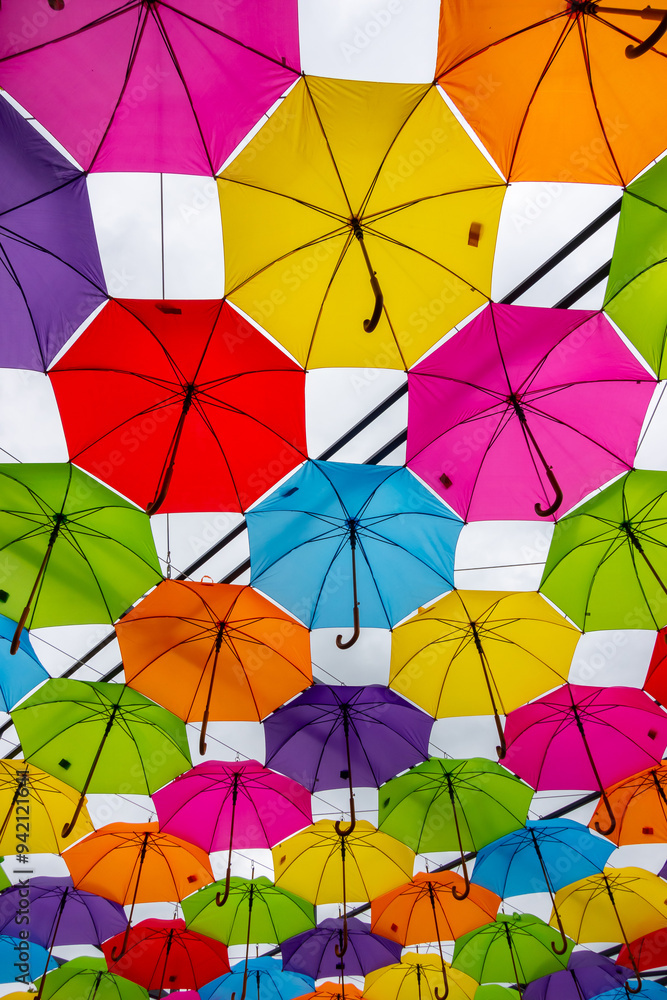 Many colorful umbrellas against the sky. Vivid colour installation made of umbrellas photographed from below.