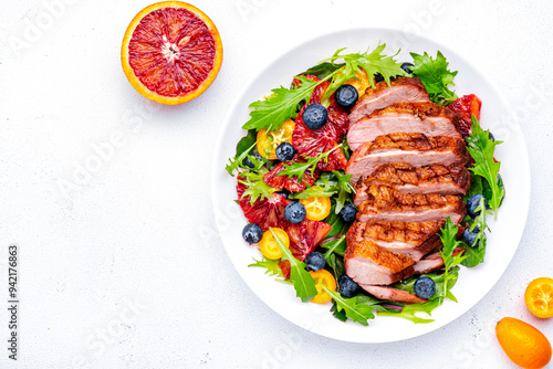 Fresh salad with grilled duck and sicilian orange, blueberry, chard, lettuce and arugula on white background, top view photo