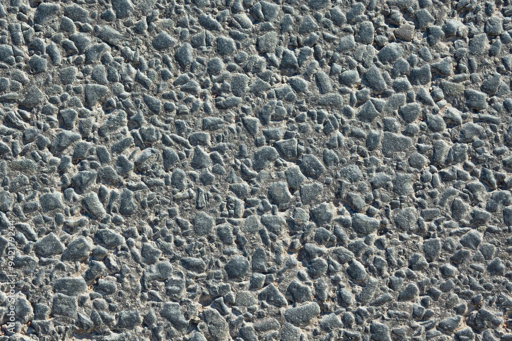 Close-up of fresh asphalt on a road. Small stones are glued together with black bitumen mass. Background. Texture