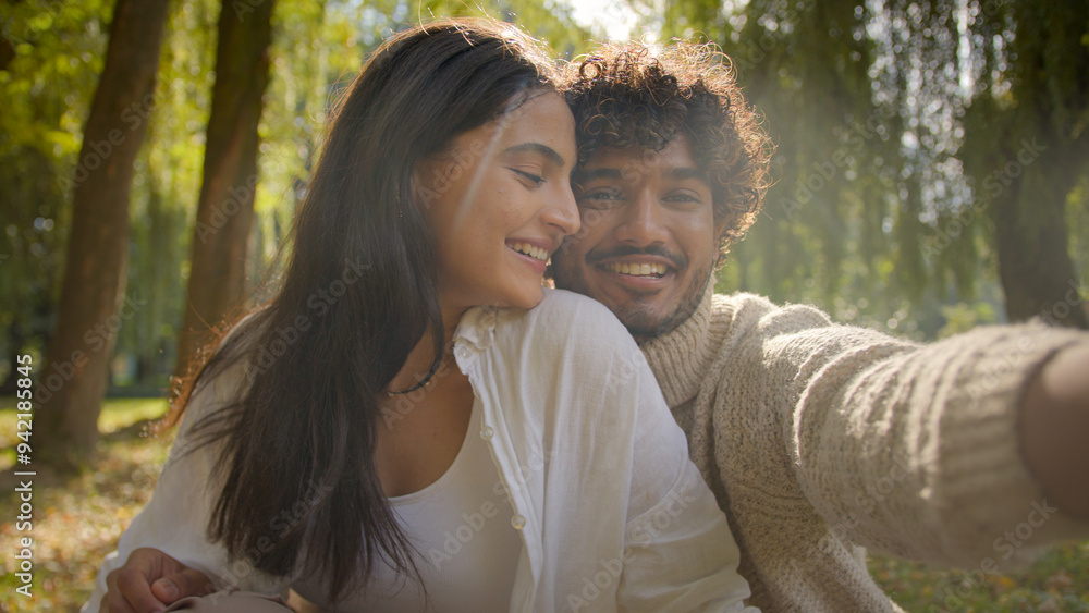 Carefree multiracial couple Arabic Indian male boyfriend happy Hispanic girlfriend woman making photo on mobile phone device outside in park man female laugh smile filming video cuddle honeymoon love