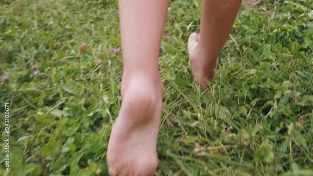 A child walks barefoot through soft, vibrant grass, exploring the joys of nature. The close-up shot captures the essence of carefree summer days. A child walks barefoot through soft, vibrant grass, exploring the joys of nature. The close-up shot captures the essence of carefree summer days.