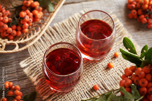 Homemade herbal syrup in two shot glasses with fresh wild orange rowanberry