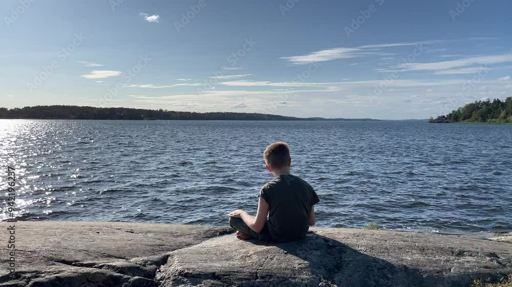 Kid at a Lake. Relaxing on the cliffs. Mälaren, Stockholm, Sweden. August 2024. Kid at a Lake. Relaxing on the cliffs. Mälaren, Stockholm, Sweden. August 2024.