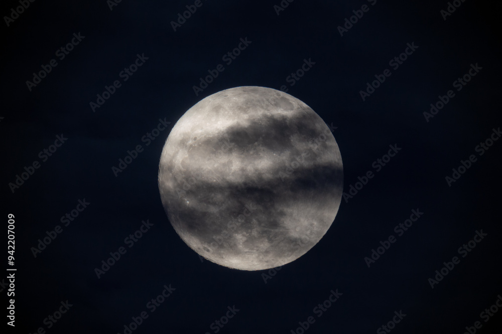 photograph of the full moon partially covered with clouds