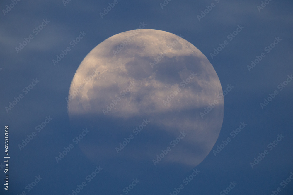 photograph of the full moon partially covered with clouds