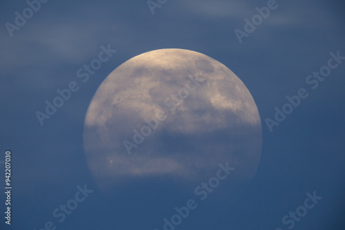 photograph of the full moon partially covered with clouds