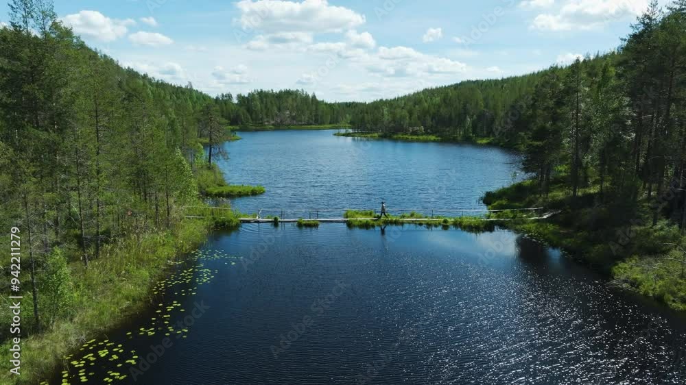 AERIAL: Person walking over a bridge in middle of forests of Pirkanmaa, Finland AERIAL: Person walking over a bridge in middle of forests of Pirkanmaa, Finland