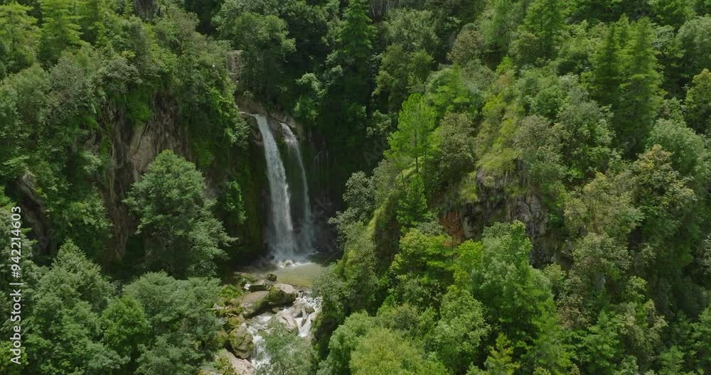 A tranquil drone shot capturing a serene waterfall hidden within a lush green forest in Nepal, bathed in sunlight. The vibrant scenery showcases nature's beauty and peaceful ambiance. A tranquil drone shot capturing a serene waterfall hidden within a lush green forest in Nepal, bathed in sunlight. The vibrant scenery showcases nature's beauty and peaceful ambiance.