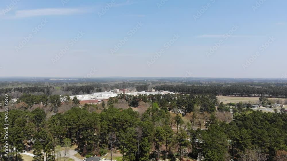 A flyover of Raeford North Carolina with Homes Trees and Factory off in the distance A flyover of Raeford North Carolina with Homes Trees and Factory off in the distance