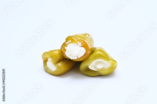 three hot green peppers stuffed with cheese on a white background