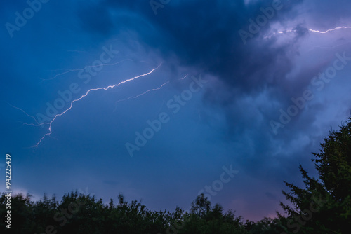 Thunderstorm, electrostatic discharge in the night sky, branching lightning high above the clouds. View of the dark sky. photo