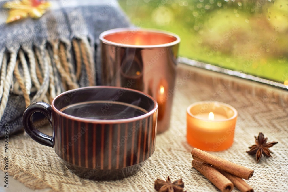 Warm cozy composition on the window. It's raining outside, warm tea with cinnamon and candles on the windowsill. Autumn concept. Warm cozy composition on the window. It's raining outside, warm tea with cinnamon and candles on the windowsill. Autumn concept.