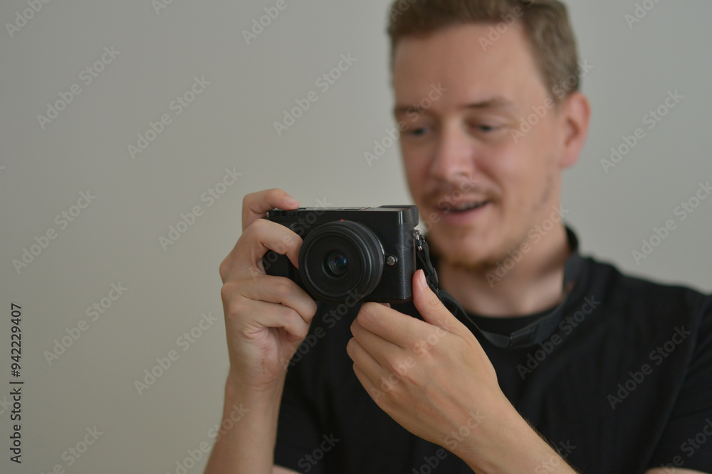 Young man with a photocamera. The photographer looks emotionally at the photo on the camera screen. Professional photographing concept Young man with a photocamera. The photographer looks emotionally at the photo on the camera screen. Professional photographing concept