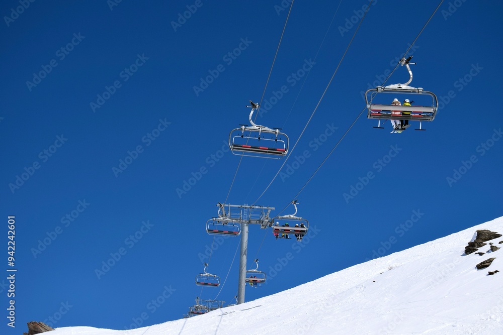 Overhead chair lifts for skiers and snowboarders on a clear, sunny day in a French ski resort Overhead chair lifts for skiers and snowboarders on a clear, sunny day in a French ski resort