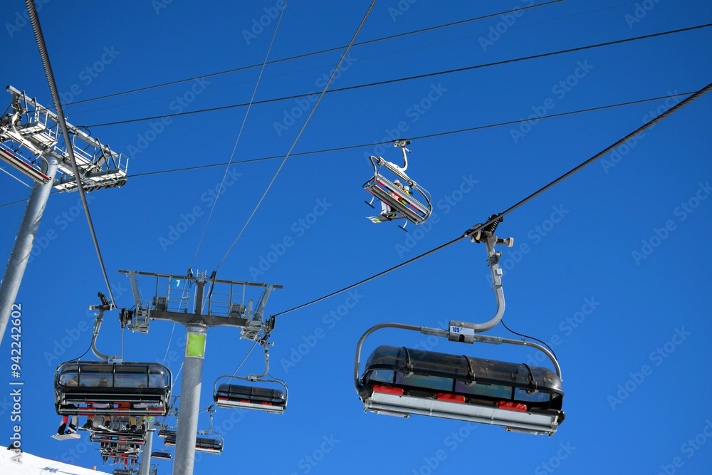 Overhead chair lifts for skiers and snowboarders on a clear, sunny day in a French ski resort Overhead chair lifts for skiers and snowboarders on a clear, sunny day in a French ski resort
