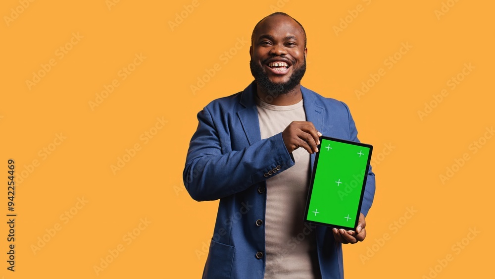 Amused african american man laughing while presenting tablet with green screen display, studio background. Joyous BIPOC person has fun during promotion for blank copy space mockup device, camera B Amused african american man laughing while presenting tablet with green screen display, studio background. Joyous BIPOC person has fun during promotion for blank copy space mockup device, camera B