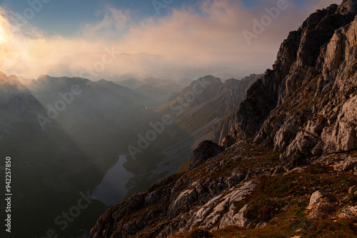 A Sunset at the Durmitor peak, Bobotom Kuk, overlooking a lake in the valley while sunrays pierce through
