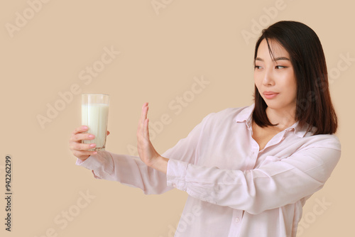 Young Asian woman with lactose intolerance on beige background