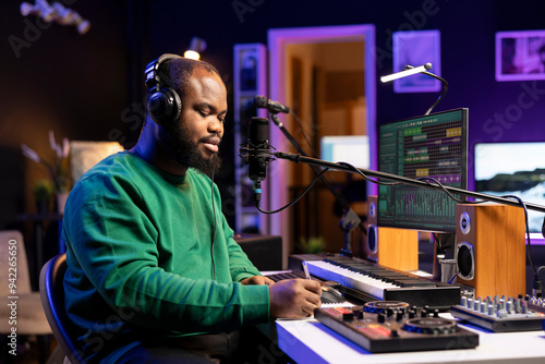 Skilled musician artist creating a new track in his home studio, thinking about verses to fit the rhymes and rhythm. Composer singer writing down lyrics to create a soundtrack, acoustical engineering.