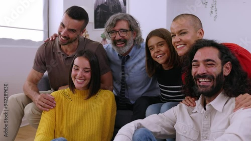 Side view of multigenerational happy family sitting together on sofa at home. Photo group of grandfather, mother, father, aunt, ancle and granddaughter relaxing in the living room. photo