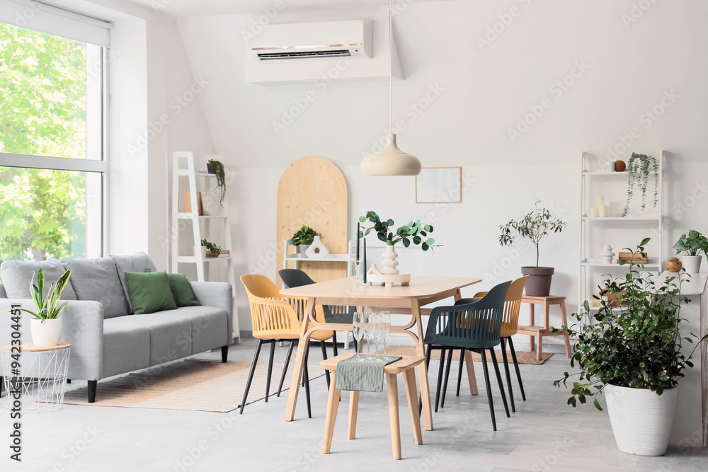 Interior of light room with dining table, sofa and plants Interior of light room with dining table, sofa and plants