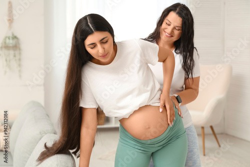 Happy doula supporting beautiful young pregnant woman at home photo