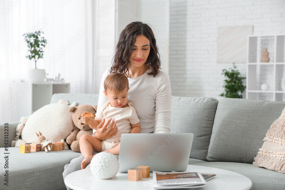 Cute little baby and happy young mother working with laptop on maternity leave at home Cute little baby and happy young mother working with laptop on maternity leave at home