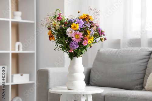 Vase with wild flowers on coffee table in interior of living room. Closeup