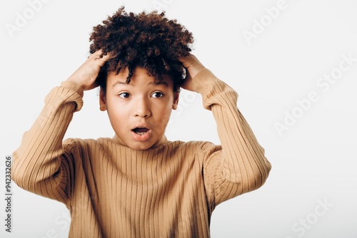 Young african american girl with hands on her head and a surprised expression, gazing upward in awe photo