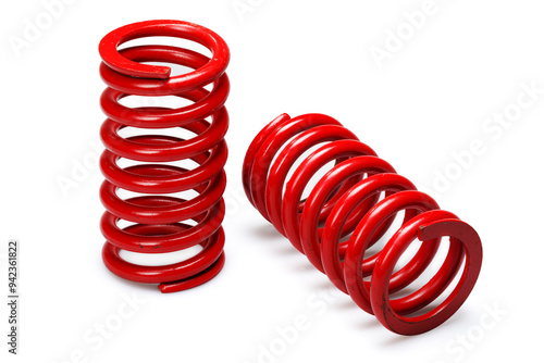 Studio photography of a set of automotive suspension springs with soft shadows isolated on a white background. Close-up shot of two large red coil springs for car wheels.