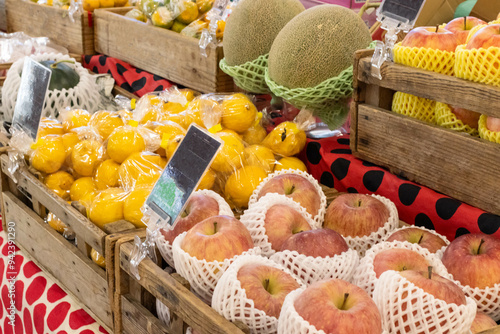 Assortment of fruits such as apple, melon, lemon and watermelon in wooden box and foam sleeve at fruit stall in market photo