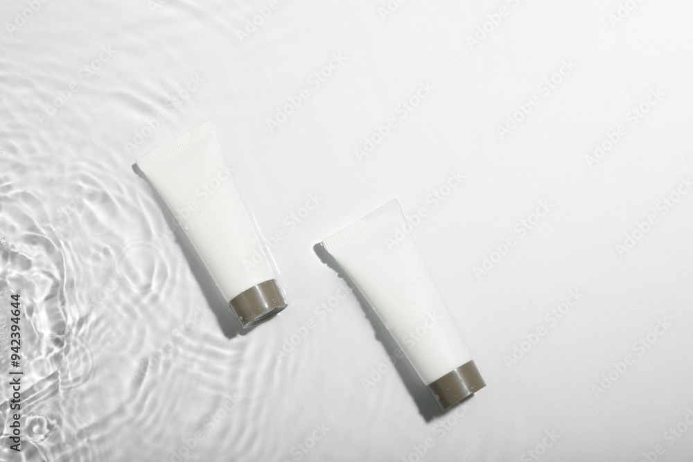 Cosmetic products. Tubes with cream in water on light background, top view Cosmetic products. Tubes with cream in water on light background, top view
