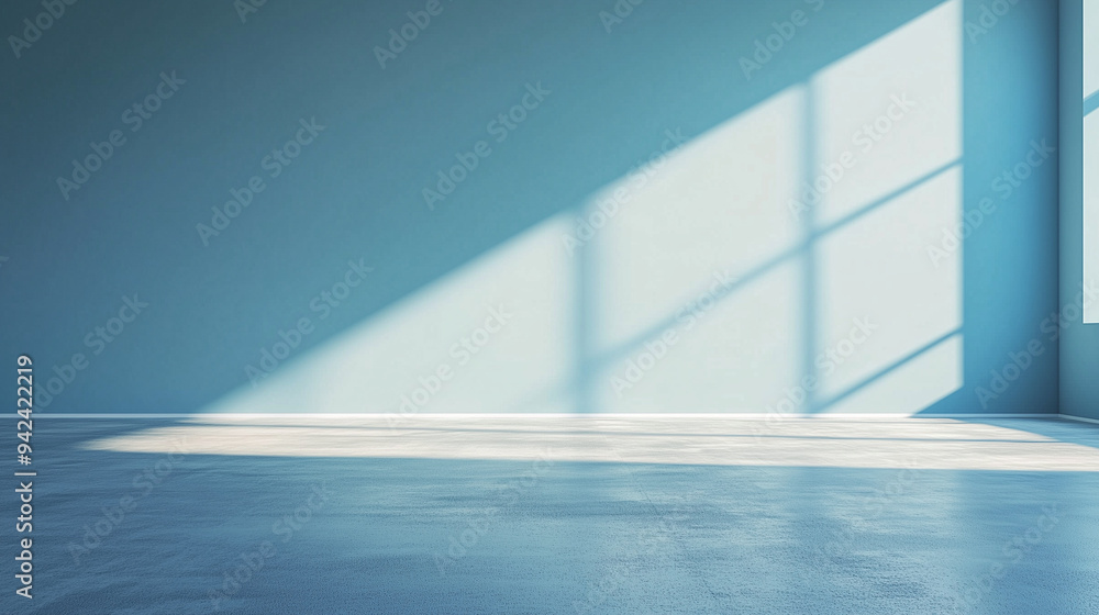 Sunlight is casting shadows from a window in an empty room with blue walls and a polished concrete floor Sunlight is casting shadows from a window in an empty room with blue walls and a polished concrete floor
