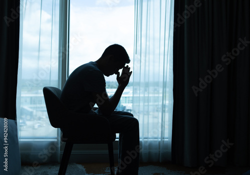 silhouette of man praying sitting in his room 