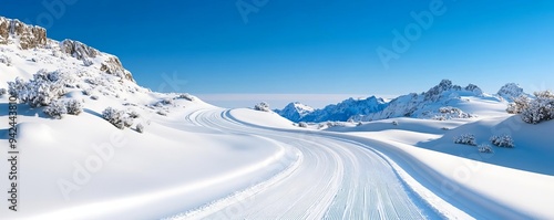Snow-covered mountain road with a clear blue sky, winter adventure