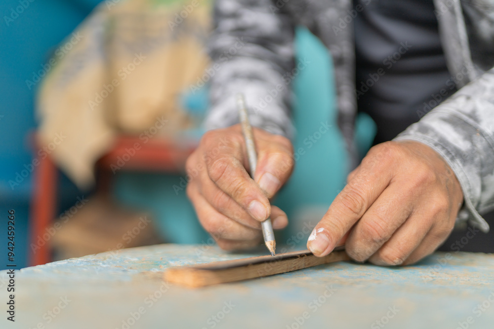 Woodcarver measuring wooden plank with pencil Woodcarver measuring wooden plank with pencil