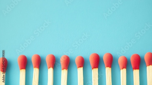 Close-up of several red-tipped matchsticks aligned in a row on a vibrant blue background, showcasing simplicity and contrast.