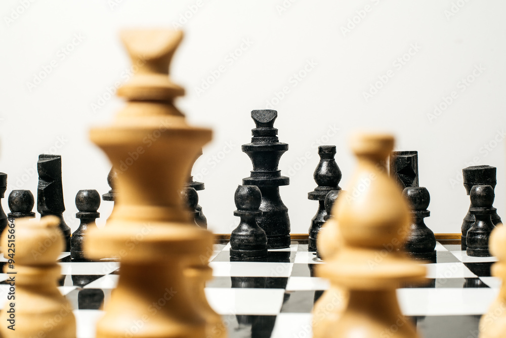 Close-up of a chessboard, focusing on the black king surrounded by blurred wooden pieces, symbolizing the intense strategic battle unfolding Close-up of a chessboard, focusing on the black king surrounded by blurred wooden pieces, symbolizing the intense strategic battle unfolding