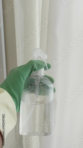 CloseUp of a Hand Firmly Holding a Clear Spray Bottle in a Spotlessly Clean Environment photo