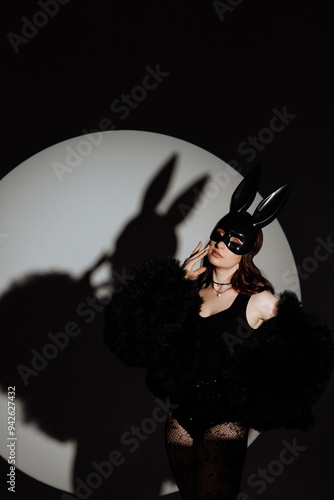 A woman in a black outfit with a rabbit mask on her face. The image has a dark and mysterious mood photo