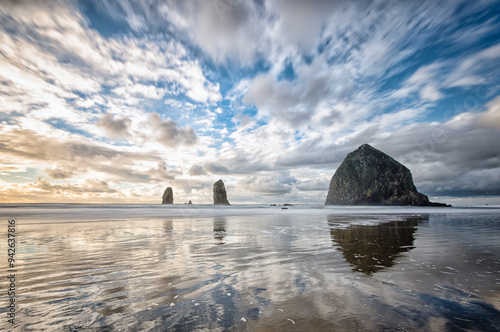 A long exposure of Haystack rock at sunset with flowing clouds