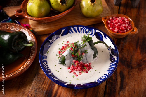 Chiles en Nogada, Typical dish from Mexico. Prepared with poblano chili stuffed with meat and fruits and covered with a walnut sauce, parsley and pomegranate. photo