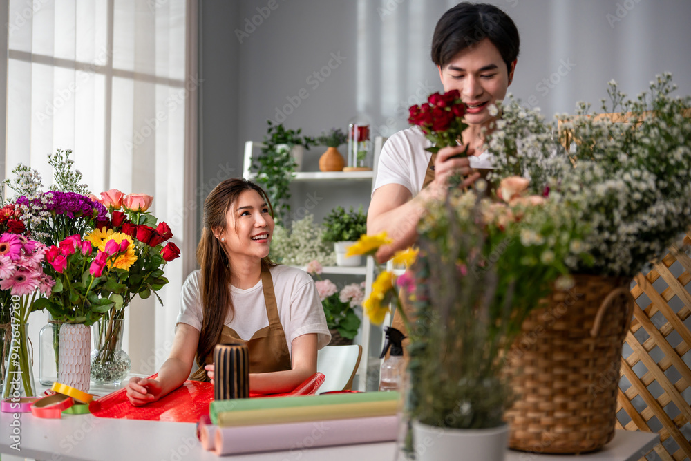 Asian young florist couple completing beautiful bouquet in flower shop. Asian young florist couple completing beautiful bouquet in flower shop.