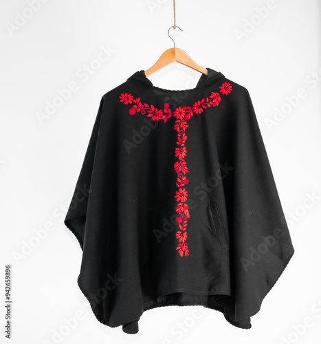 Hand embroidered sheep wool poncho, colorful, flower embroidery, black poncho on white background, no people, Ecuadorian poncho, Andean, handicraft.