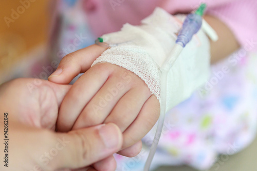 Quadro su tela Mother holding child hand with saline IV solution in hospital