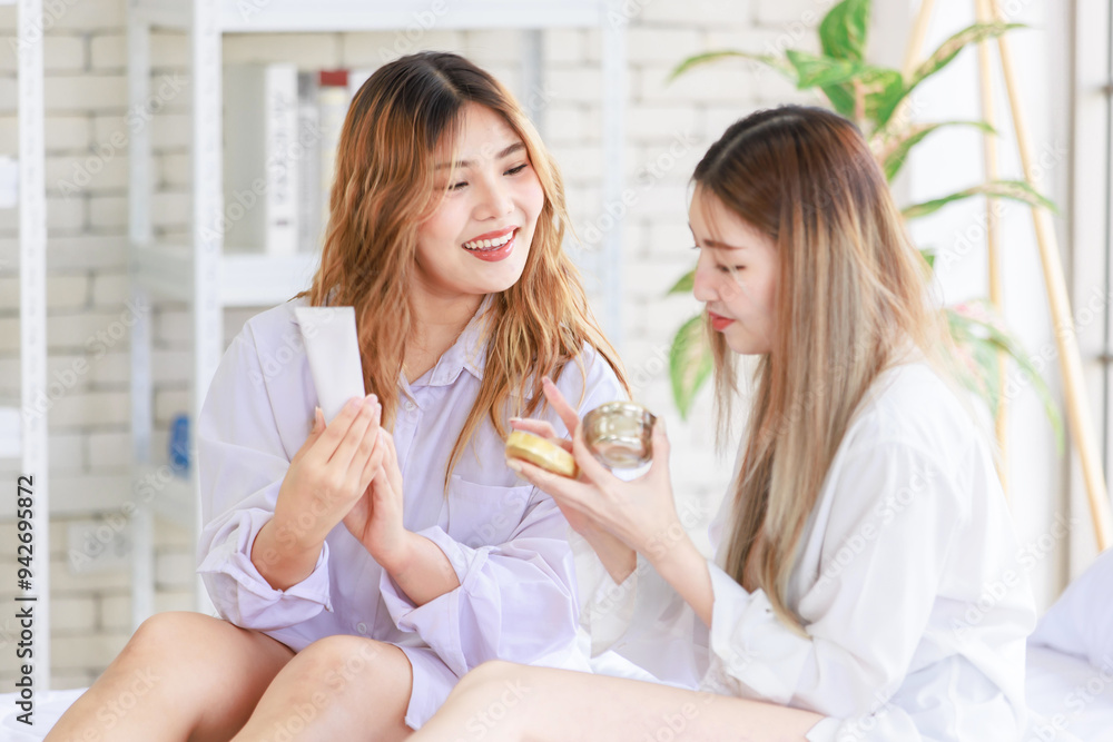Two happy beautiful Asian female girlfriends with cosmetics make face take care of skin, Attractive women trying beauty products relax on a white bed, Concept teenage or friends lifestyle at home. Two happy beautiful Asian female girlfriends with cosmetics make face take care of skin, Attractive women trying beauty products relax on a white bed, Concept teenage or friends lifestyle at home.
