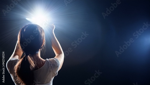 A woman holding a bright light in a dark space, symbolizing hope and inspiration through illumination and creativity. photo