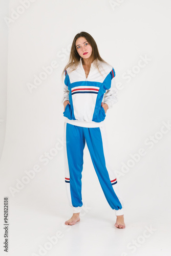 Girl with long hair in a tracksuit in full growth on a white background.