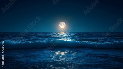 Full moon casting light over calm ocean waves at night photo